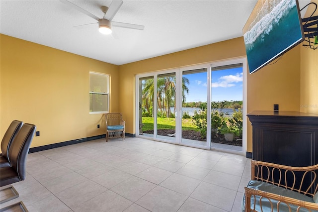 office space with a water view, baseboards, a ceiling fan, and tile patterned floors