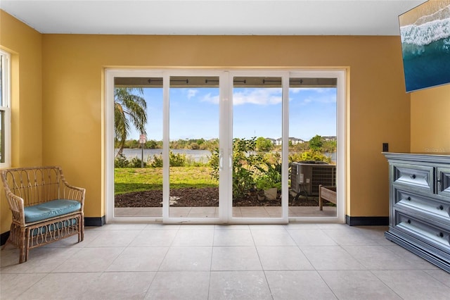 doorway to outside with tile patterned flooring, a water view, and baseboards