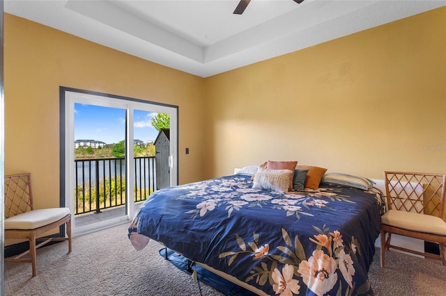 bedroom featuring a raised ceiling, access to outside, carpet flooring, and a ceiling fan