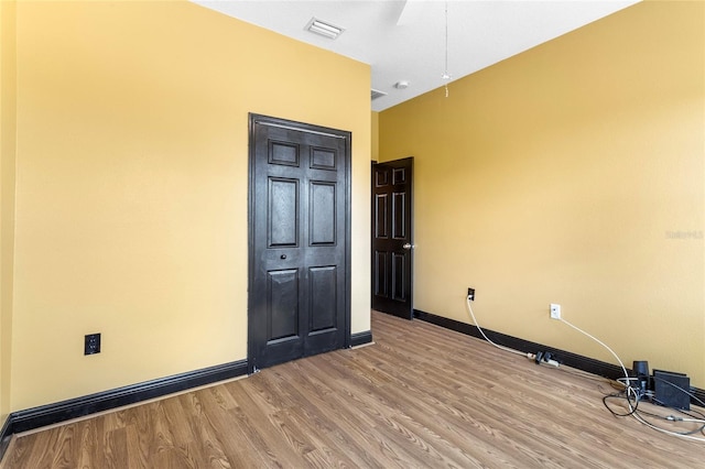 spare room featuring light wood finished floors, visible vents, and baseboards