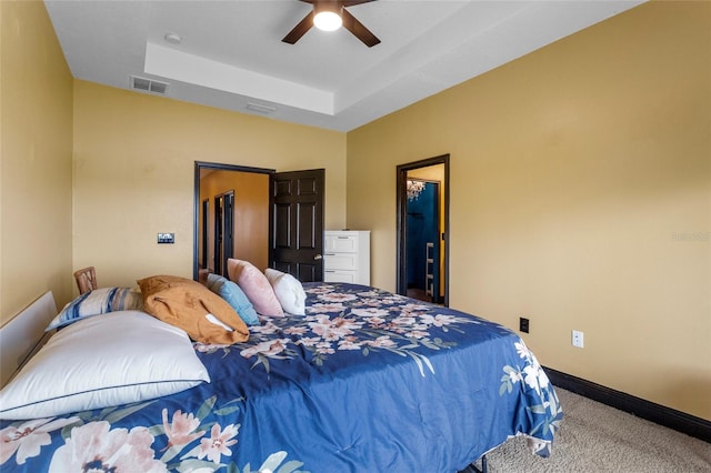 carpeted bedroom with a raised ceiling, visible vents, ceiling fan, and baseboards