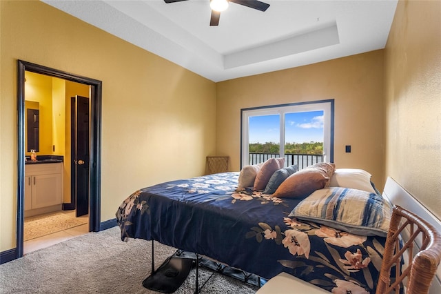 bedroom with access to exterior, a raised ceiling, light carpet, connected bathroom, and baseboards