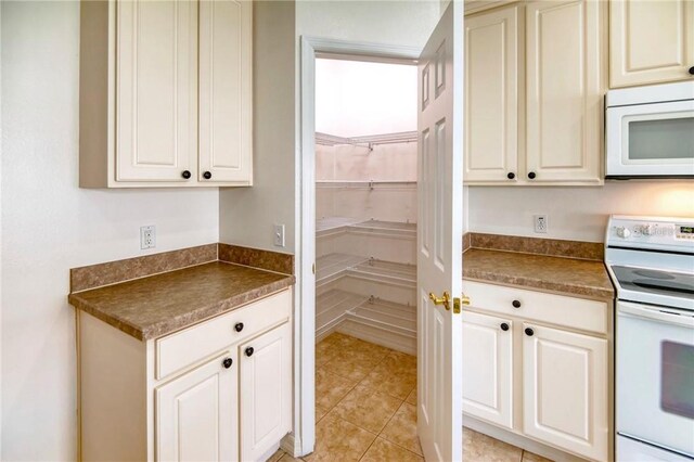 153 Ventana Dr, Poinciana, FL 34759 - kitchen featuring light tile patterned floors, white appliances, and dark countertops