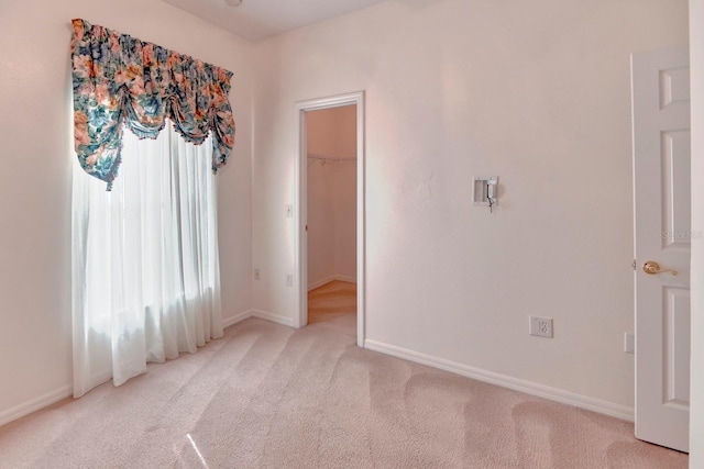 153 Ventana Dr, Poinciana, FL 34759 - unfurnished bedroom with light carpet, multiple windows, a walk in closet, and baseboards