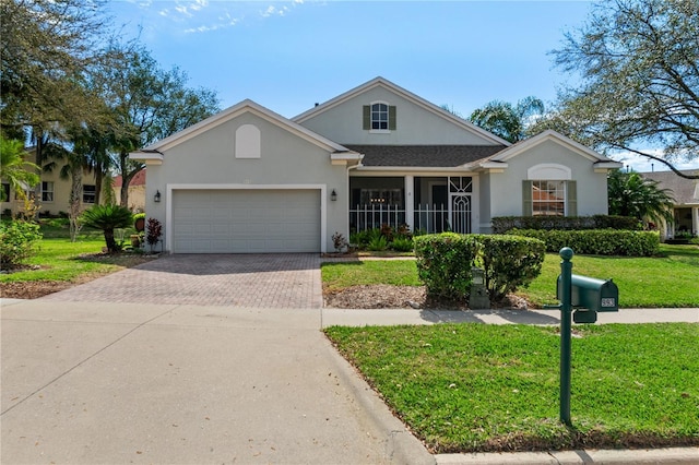 single story home with a garage, decorative driveway, a front yard, and stucco siding