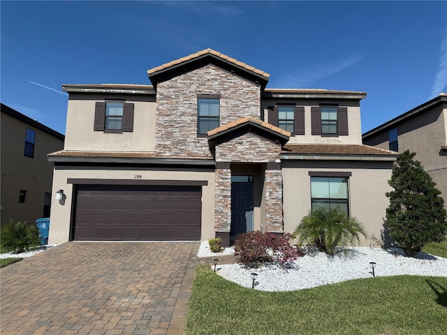 view of front of house featuring stucco siding, stone siding, a garage, and decorative driveway