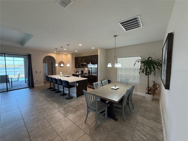 dining area with visible vents, arched walkways, and baseboards