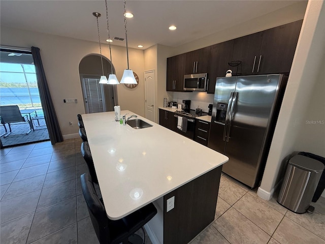 kitchen featuring a sink, light countertops, decorative backsplash, appliances with stainless steel finishes, and a kitchen island with sink