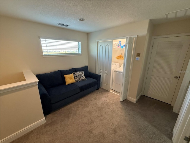 living area with washing machine and clothes dryer, visible vents, baseboards, carpet, and a textured ceiling