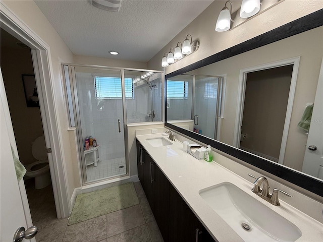 bathroom with a shower stall, a textured ceiling, toilet, and a sink