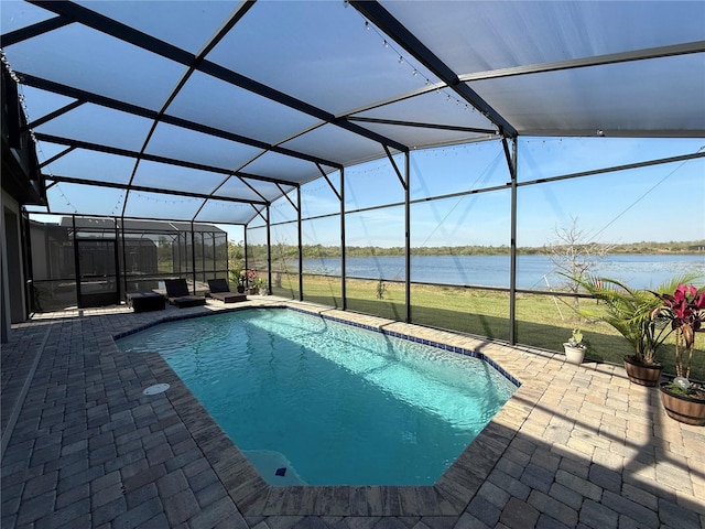 outdoor pool featuring glass enclosure, a patio, and a water view