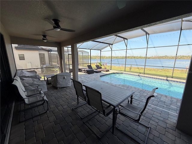 pool with a patio area, a lanai, ceiling fan, and a water view