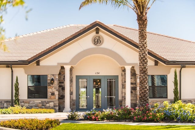 199 Macaulays Cv, Haines City, FL 33844 - doorway to property with a tile roof, stucco siding, stone siding, and french doors