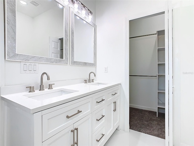 full bath with visible vents, a sink, a spacious closet, and double vanity