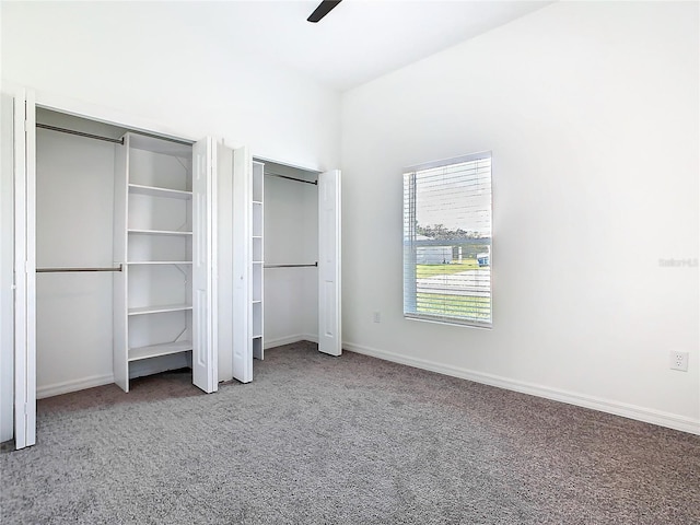 unfurnished bedroom featuring baseboards, ceiling fan, carpet flooring, and multiple closets