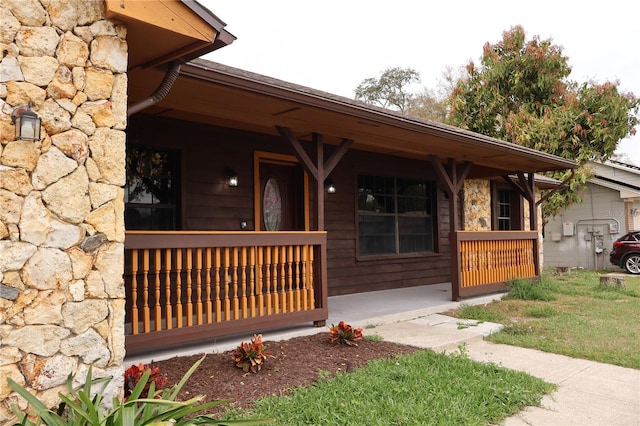 entrance to property with stone siding and a porch