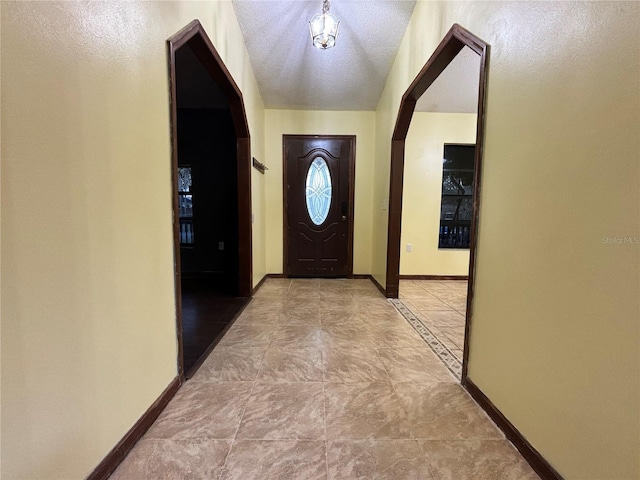 doorway featuring a textured ceiling and baseboards