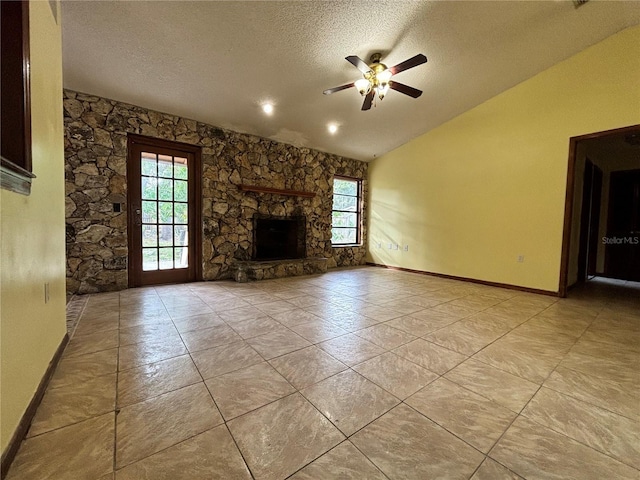 unfurnished living room featuring a textured ceiling, a stone fireplace, lofted ceiling, and a wealth of natural light