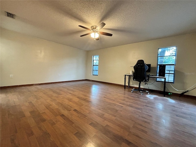 home office featuring a ceiling fan, a textured ceiling, baseboards, and wood finished floors