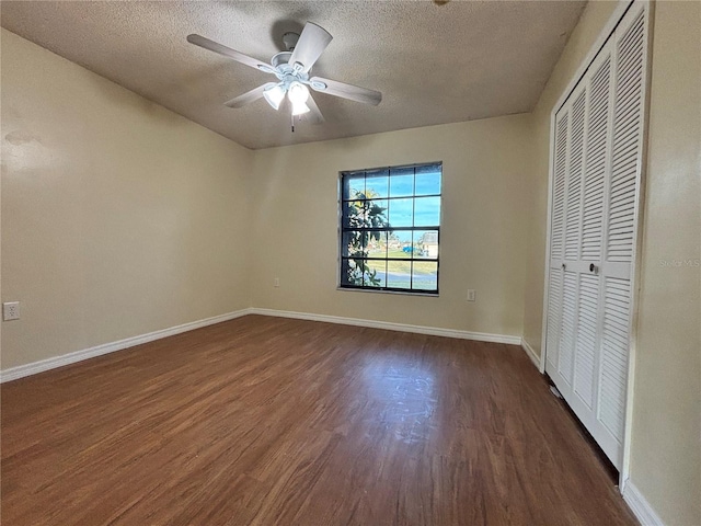 unfurnished bedroom with a textured ceiling, baseboards, dark wood-style flooring, and a closet