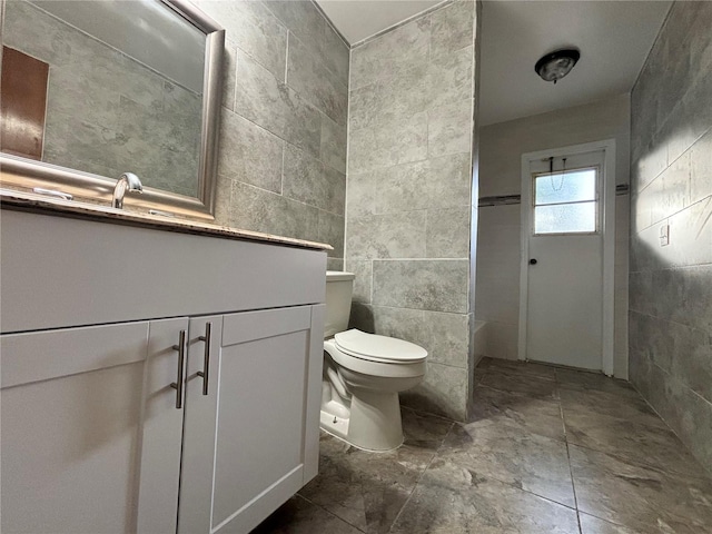 bathroom featuring toilet, tile walls, and vanity