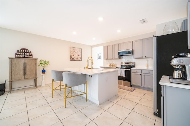 kitchen with visible vents, gray cabinets, stainless steel appliances, a sink, and light tile patterned flooring