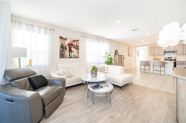 living room with light wood-type flooring, visible vents, and recessed lighting