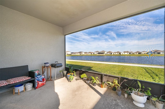 sunroom / solarium featuring a water view and a residential view