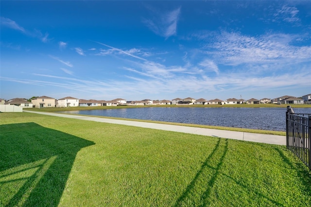 view of yard with a residential view, a water view, and fence