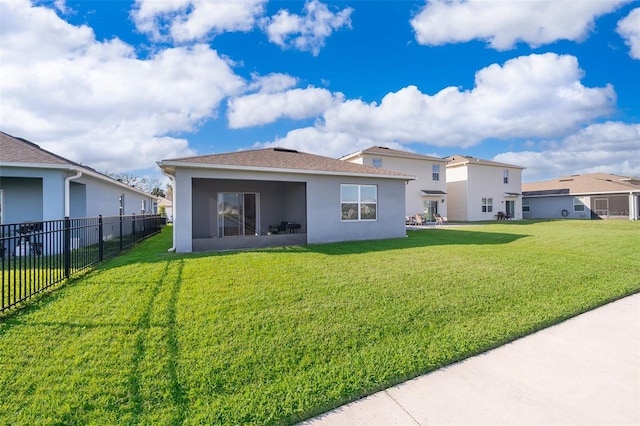 rear view of house featuring a yard, fence, a residential view, and stucco siding