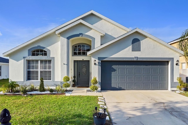 view of front facade with stucco siding, an attached garage, concrete driveway, and a front lawn