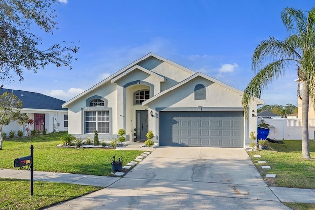 ranch-style home with stucco siding, fence, concrete driveway, a front yard, and a garage