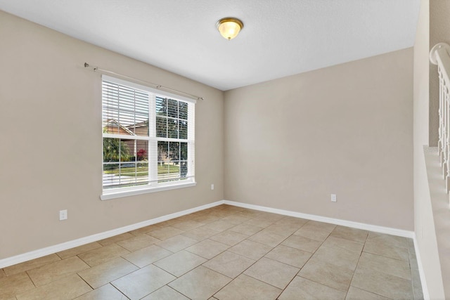 empty room with light tile patterned floors and baseboards