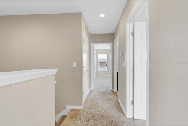 corridor with carpet floors, attic access, and baseboards