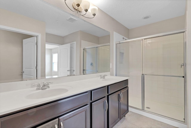 bathroom with tile patterned flooring, visible vents, a sink, and a shower stall