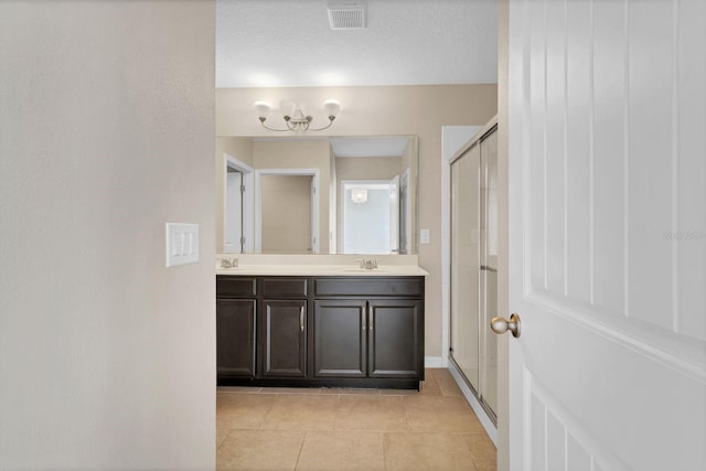 bathroom featuring double vanity, visible vents, a sink, a shower stall, and tile patterned flooring