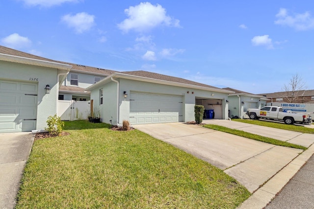 view of front of home with stucco siding, an attached garage, a front yard, fence, and driveway