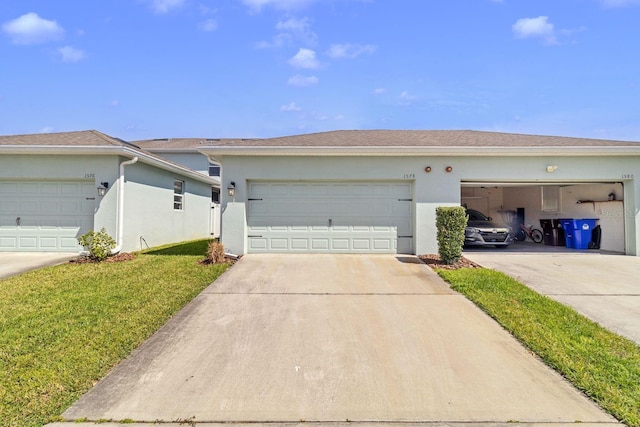 view of front of home with concrete driveway, an attached garage, a front lawn, and stucco siding