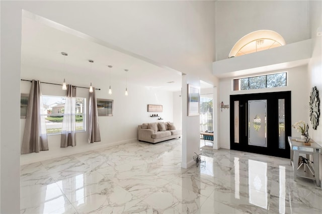 entrance foyer featuring a towering ceiling, marble finish floor, and a wealth of natural light