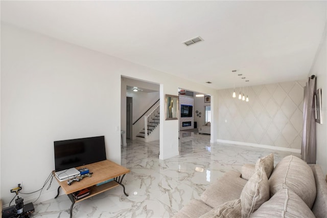 living area featuring marble finish floor, visible vents, an accent wall, baseboards, and stairs