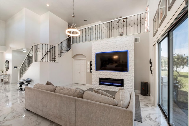 living room featuring a high ceiling, a fireplace, visible vents, stairs, and marble finish floor