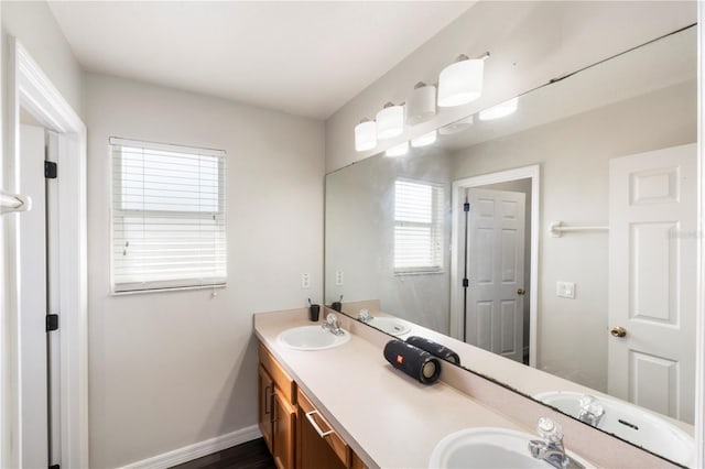 bathroom with double vanity, baseboards, and a sink