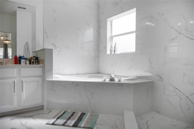 full bathroom with visible vents, a garden tub, vanity, and stone wall