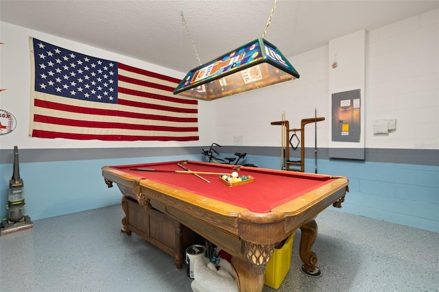 playroom with a textured ceiling, pool table, speckled floor, electric panel, and concrete block wall