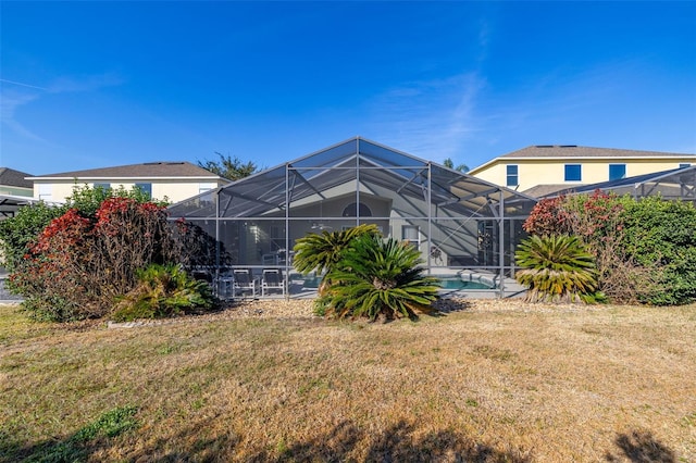 rear view of property featuring a lawn, stucco siding, a lanai, and an outdoor pool