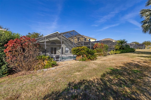 rear view of property featuring a lanai and a lawn