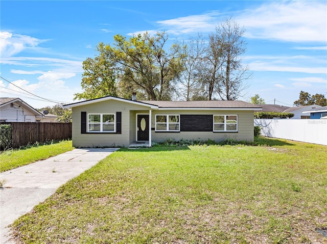 ranch-style home featuring fence and a front lawn