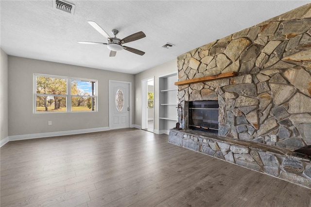 unfurnished living room with a fireplace, visible vents, a textured ceiling, and wood finished floors