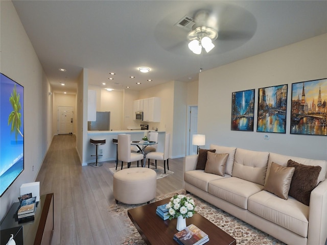 living room featuring recessed lighting, visible vents, light wood-style flooring, and baseboards