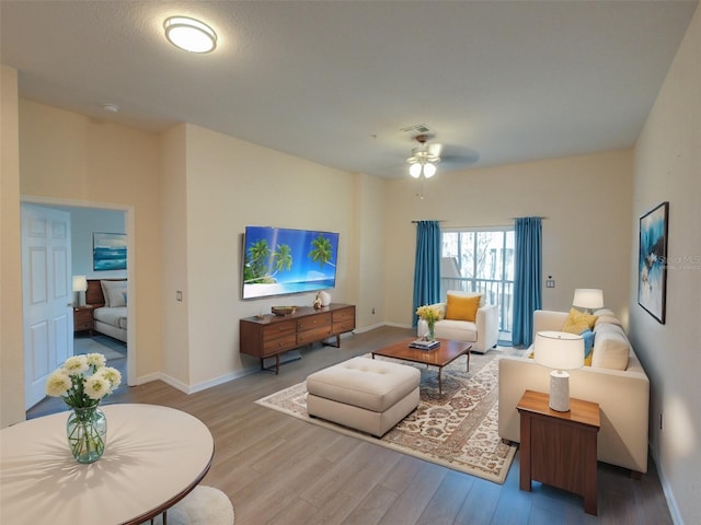 living area featuring visible vents, baseboards, ceiling fan, and wood finished floors